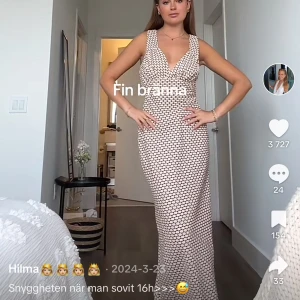 Lång  klänning från intu fashion  - Supersnygg långklänning från Intu fashion med exklusivt geometriskt mönster i beige och brunt. Djup v-ringning, breda axelband och figurnära passform. Tillverkad i glansigt satinliknande material som känns lyxigt och unikt.