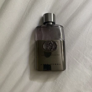Gucci Guilty Pour Homme parfym - Gucci Guilty Pour Homme parfym i en stilren flaska med metallisk grå botten och transparent övre del. Flaskan har Guccis ikoniska logga ingraverad och ett snyggt, modernt utseende. Perfekt för dig som gillar exklusiva dofter och snygg design.