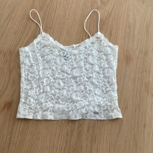 Vitt spetsigt linne - Supersött vitt linne från H&M Divided i storlek XS. Toppen är helt i spets med blommigt mönster och tunna axelband.