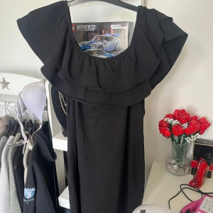 Svart volangklänning från H&M - Supersnygg svart klänning från H&M i storlek L. Klänningen har bred volang runt axlarna och en luftig passform. 