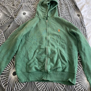 Grön hoodie från Polo Ralph Lauren   - Grön hoodie från Polo Ralph Lauren storlek(m) med dragkedja och huva. Klassisk orange logga på bröstet 
