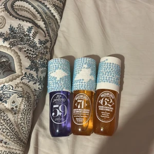 Sol de Janeiro Cheirosa parfymtrio - Tre Sol de Janeiro Brazilian Crush Cheirosa body mists: 59 (lila flaska), 71 (bärnstensfärgad flaska) och 62 (bärnstensfärgad flaska). Flaskorna har vita korkar dekorerade med blå glittriga stenar för extra bling. Perfekt för dig som älskar söta och gourmandiga dofter. Alldrig använd 