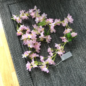 Blommig ljusslinga med rosa blommor - Superfin ljusslinga med konstgjorda rosa blommor och gröna blad. Slingan drivs med batteri och har en transparent batteridosa. den är ca 1,5m lång. den väger ingenting så är lätt att sätta upp, (den sista bilden på spegeln är vad jag personligen har använt den till)  