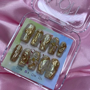 GLD3N (S);Medium Square - Snygga gelé press on-naglar i storlek S: 15 mm, 11,5 mm, 12 mm, 11 mm, 9 mm , med skimrande guldmönster och 3D-blommor. Basen är ljus och glittrig, dekorerad med swirliga gulddetaljer och pärlliknande blommor. 