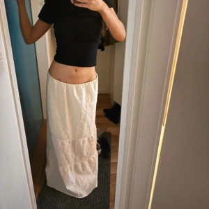 Vit långkjol i bomull - Säljer en vit långkjol med avslappnad passform och lätt rynkade sömmar. Kjolen har en enkel och stilren look, perfekt för dig som gillar en clean och luftig vibe. Tillverkad i mjuk bomull som känns skön mot huden.