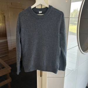 Mörkgrå stickad tröja med rund hals - En stilren mörkgrå stickad tröja från Arket med rund halsringning och långa ärmar. Tröjan har en klassisk passform och ribbade muddar vid ärmslut och nederkant. Perfekt för lager-på-lager och enkel att matcha med jeans eller kjol. Storlek XS men passar S, hör av er för frågor eller funderingar!🙌🏻