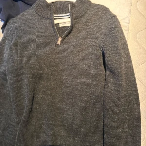 Grå stickad tröja med half zip Pier One - Mysig grå stickad tröja från Pier One med half zip-dragkedja vid halsen. Tröjan har en ribbad krage och är långärmad, perfekt för kyliga dagar. Enkel och stilren design som funkar till många olika outfits.