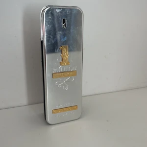 1 Million Lucky parfym från Paco Rabanne - 1 Million Lucky från Paco Rabanne i en snygg, rektangulär flaska med spegelblank silverfinish och detaljer i guld. Flaskan har en modern och lyxig design med inslag av brunt glas på baksidan. Rymmer 100 ml. No box