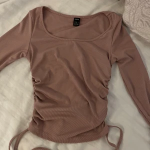 Ribbad beige, rosa långärmad topp från SHEIN - Supersnygg ribbad topp i beige från SHEIN med långa ärmar och trendig snörning i sidorna. Modellen är figurnära med rundad halsringning och croppad känsla.