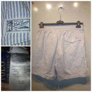 Randiga badshorts Polo Ralph Lauren M - Snygga blåvit randiga badshorts från Polo Ralph Lauren med klassisk orange logga broderad på benet. Shortsen har elastisk midja med snörning, bakficka med knapp och innerbyxa i mesh. Perfekta för stranden eller poolen.  Fint skick inget att anmärka. Nypris 1495kr.