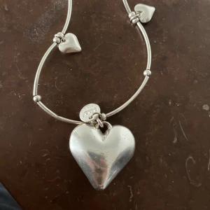 Halsband i silver med hjärtan från Dyrberg/Kern - Stilrent halsband i silverfärgad metall från Dyrberg/Kern med flera små hjärtan och ett större hjärthänge. Kedjan har dekorativa kulor mellan länkarna och ger ett romantiskt intryck. Perfekt accessoar för att lyfta din outfit.