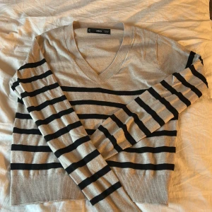 Randig beige tröja från Mango - Snygg beige tröja från MNG med svarta horisontella ränder. Tröjan har v-ringning, långa ärmar och är i ett tunt, mjukt material 