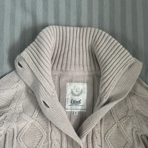 Beige cardigan - Snygg beige stickad cardigan från Etirel med grov ribbad krage och stora knappar framtill.  Mycket bra skick och Storlek S