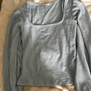 Ljusblå ribbad topp från Bik Bok - Supersöt ljusblå långärmad topp från Bubbleroom! fyrkantig uringning och ribbad struktur. Helt oanvänd med kappen kvar!