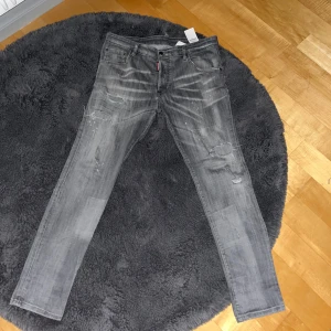 Grå skinny jeans från Dsquared2 - Snygga grå jeans från Dsquared2 med slitna detaljer och diskreta färgstänk. Modellen är skinny fit med klassisk femficksdesign och låg midja. Jeansen har Dsquared2-logga på röd etikett och är tillverkade i bomull. Perfekta för dig som gillar streetstyle.