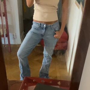 Ljusblå bootcut jeans - Säljer ett par ljusblå jeans med bootcut-modell och klassisk femficksdesign. Jeansen har låg midja och är tillverkade i mjukt denimtyg. Perfekta för en avslappnad och trendig look.