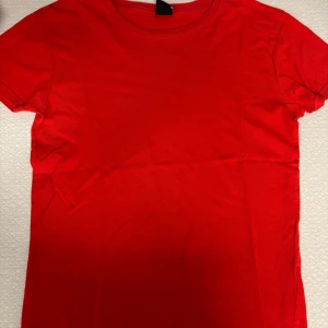 Röd basic t-shirt i bomull - En enkel och stilren röd t-shirt i mjuk bomull. Klassisk rund halsringning och korta ärmar. Perfekt att matcha med jeans eller shorts för en clean look.
