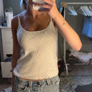 Vit blommig linnetopp Brandy Melville - Supersöt vit linnetopp från Brandy Melville med små blommiga mönster i ljusrosa. Tunt och mjukt bomullstyg och smala axelband. Köpte 2023 men har knappt använt! skulle säga att den passar XXS-S❣️