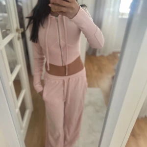 Ljusrosa croppad hoodie Boohoo -  ljusrosa croppad hoodie från Boohoo med dragkedja framtill och snörning samt matchande mjukisbyxor till. Både tröjan och byxorna är i storlek xs. 
