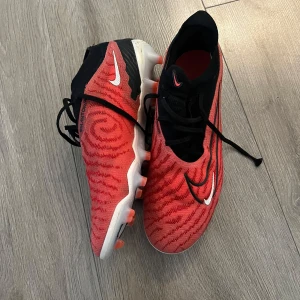 Nike Phantom Elite - Röda Nike Phantom Elite. Storlek 42,5. Använda men inget fel på dem. Har bytt snöre på högra skon! Men original. Skon finns ej tillgänglig att köpa online så ändas fåtal kvar! 🫣Kom med Pris förslag