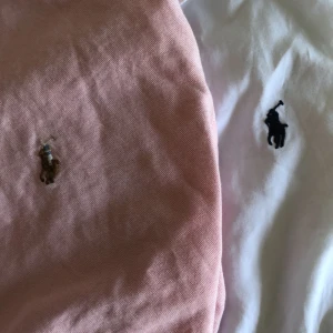 Två skjortor i rosa och vitt - Två klassiska skjortor i bomull, en i ljusrosa och en i vit. Båda har knappar framtill och krage, samt lång ärm. Perfekta för en clean och stilren look. Passar dig som gillar enkel och tidlös stil.