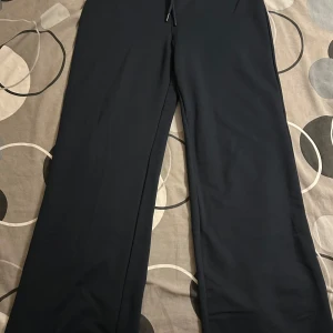 Svarta mjukisbyxor från 157, storlek M - Svarta mjukisbyxor från 157 i storlek M, helt oanvända. Byxorna har raka ben och dragsko i midjan för skön passform. Perfekta för chill dagar eller när du vill ha det extra bekvämt. Materialet känns mjukt och följsamt.