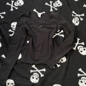 Svart långärmad topp från H&M XS - En svart långärmad topp från H&M i storlek XS. Modellen är figurnära med rundad urringning och liten rosett framtill. Tillverkad i mjuk bomull, perfekt för lager-på-lager eller som enkel bas i garderoben. Plagget är handsytt, vilket innebär att det kan förekomma mindre skavanker tex lösa trådar! 🪡 