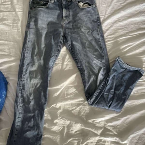 Loose fit ljusblå jeans från Weekday - Loose fit jeans från Weekday i en snygg ljusblå tvätt. Klassisk femficksmodell med raka ben och normal midja. Jeansen har slitna detaljer och tydliga sömmar, perfekta för en avslappnad streetstil.