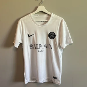 Vit PSG x Balmain  - Säljer min Psg x Balmain tröja då den bara kom till användning 1 gång. Jätte fint skick och snygg passform. Inget slitage eller liknande. Perfekt nu till sommaren
