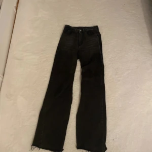 Svarta raka jeans med rå kant - Säljer ett par svarta jeans med rak passform och råa, avklippta benslut. Jeansen har klassisk femficksdesign och hög midja. Perfekta till sneakers eller boots för en chill look. Aldrig använd.