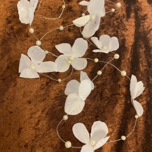 Vitt blommigt hårsmycke med pärlor - Superfint hårsmycke med vita tygblommor och pärlor på tunn silverfärgad tråd. Perfekt för att ge en romantisk och drömmig känsla till din look. Blommorna är detaljerade och pärlorna ger extra elegans. Passar perfekt till bröllop eller student , helt ny 