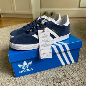 Adidas Gazelle mörkblå sneakers - Helt nya adidas gazelle, nyinköpta och aldrig använda! Säljer då jag tyvärr köpte i fel storlek och inte kan lämna tillbaka längre. Kommer i orginalförpackning. 