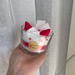 Handgjort doftljus - Doft av jordgubbar och vanilj. Bilderna visar ett handgjort ljus i glas, dekorerat med detaljer som ser ut som jordgubbar, choklad och vispgrädde. Ljuset har en söt och färgglad design med hjärtformade dekorationer, perfekt som present eller inredningsdetalj💗💗💗