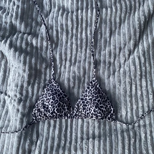 Leopardmönstrad bikiniöverdel Lager 157 - Snygg trekantsbikini från Lager 157 med leopardmönster i svart, beige och vitt. Klassisk modell med knyt i nacken och ryggen, perfekt för stranden. Tillverkad i mjukt syntetmaterial som torkar snabbt.