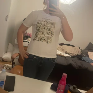 Vit t-shirt med leopardmönster från Zara - Vit t-shirt från Zara med coolt leopardmönster i beige och svart på bröstet samt texten 'SPIAGGIA DELLA PELOSA'. Klassisk passform och rund halsringning, perfekt till jeans eller shorts. Tillverkad i mjuk bomull för en skön känsla. Säljs inte längre