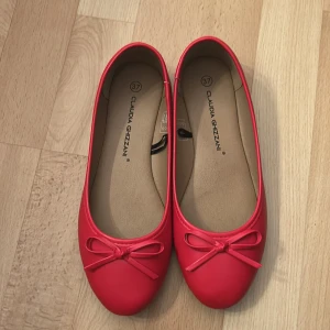 Röda ballerinaskor från Claudia Ghizzani - Snygga ballerinaskor i en röd färg från Claudia Ghizzani. Skorna har rund tå, platt sula och en söt rosett framtill. Dom har en mjuk innersula för extra komfort. Perfekta för dig som vill ha en poppig färg på fötterna. Endast använda 1 gång skulle även säga att den är 36/37 då jag vanligt vis har både 36/37💕