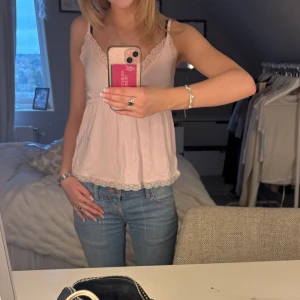 Ljusrosa spets linne -  söt ljusrosa linnetopp från Nelly med fina spetsdetaljer längs urringningen och axelbanden. Toppen har en v-ringad design, passar perfekt nu till sommaren.