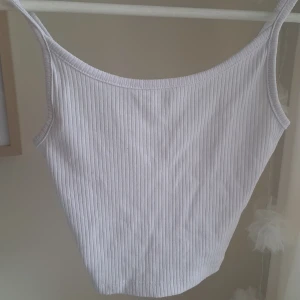 Vit ribbad linnetopp - Säljer en vit ribbad linnetopp från FB Sister  new yorker i storlek XXS. Toppen har smala axelband och är tillverkad i ett mjukt, stretchigt material. Perfekt för varma dagar eller som lager under andra plagg.