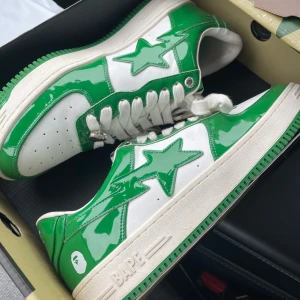 Gröna och vita Bape Sta sneakers - Säljer ett par fräscha Bape Sta sneakers i grönt och vitt med glansig finish. Skorna har klassisk stjärndesign på sidan, vita snören och perforerad tå. Kommer med originalkartong och extra skosnören. Helt nya och endast provad en gång. 
