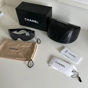 Chanel solglasögon 4126 - Snygga svarta solglasögon från Chanel med breda, glansiga skalmar och diskret logga vid gångjärnen. Modell 4126. Glasen är mörka och ger en futuristisk vibe. Kommer med originalfodral, ask och putsduk. Är i okej skick har skråmor lite här och där men har mycket användning kvar. 