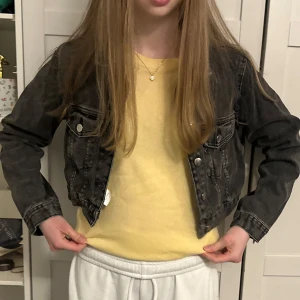 Svart croppad jeansjacka från Bik Bok - Säljer en svart croppad jeansjacka från Bik Bok. Jackan har klassisk krage, knappar framtill och två bröstfickor med lock. 