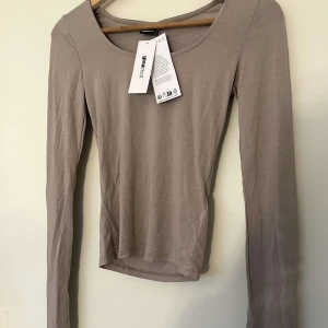 Beige långärmad topp  - Säljer en beige långärmad topp med en slits i ärmarna. Helt oanvänd 