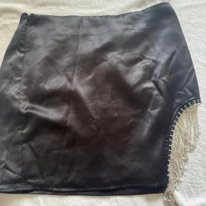 Kjol  - Svart kjol med ”glitter” detaljer på  sidan i storlek 36 från NA-KD Dragkedja finns på ena sidan. 