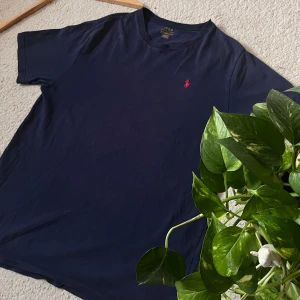 Polo Ralph Lauren T-shirt - Klassisk och stilren t-shirt från Polo Ralph Lauren i marinblå färg med den ikoniska röda loggan på bröstet 🐎 Storlek: M – passar både herr och unisex beroende på önskad passform. Tillverkad i mjuk bomull för maximal komfort ☁️ Perfekt till både vardag och mer dressade tillfällen! Fint skick – inga fläckar eller hål ✔️ 