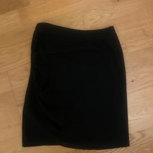 Svart tight kjol med drapering - Säljer en svart tight kjol med snygg drapering på sidan. Kjolen har en enkel och stilren design som passar perfekt till många olika outfits. Den är mjuk och stretchig. Kjolen passar många storlekar eftersom den är så pass stretchig. Den kan passa för mellan XSS-M💞