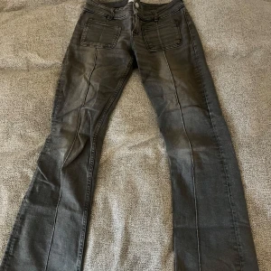 Grå bootcut jeans från Gina Tricot - Säljer ett par gråa jeans från Gina Tricot med bootcut-passform. Byxorna har två framfickor, dubbla knappar i midjan och markerade sömmar längs benen. kommer inte till användning längre 💖