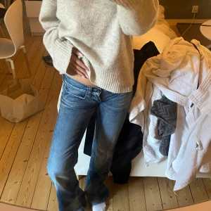 Blå lågmidjade jeans - Säljer ett par blå jeansbyxor med låg midja och klassisk femficksdesign. Jeansen har utsvängda ben och en avslappnad passform, perfekta för en casual look. Snygga detaljer med kontrastsömmar och klassisk denimtvätt.
