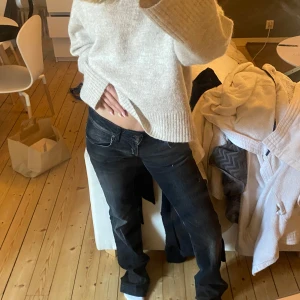 Svarta lågmidjade jeansbyxor - Säljer ett par svarta jeansbyxor med låg midja och utsvängda ben. Klassisk femficksmodell med dragkedja och knapp framtill. Perfekta för en avslappnad och trendig look.