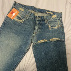 Chip pepper jeans - Säljer ett par blå jeans från Chip pepper i modellen Serenity Girl Rockies. Jeansen har slitna detaljer framtill och bak, klassisk femficksdesign och gul dekorationssöm på bakfickorna. Perfekta för dig som gillar en tuffare stil. Midjemått: 36-37 innerben:87cm PRISET KAN ALLTID DISKUTERAS 