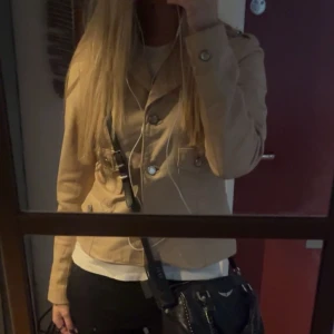 Y2K jacka - Snygg beige y2k javka som är kortare i modellen och har långa ärmar samt dekorativa knappar framtill. Köpt second hand men används ej. Bra skick. Köpt för 400. Materialet är nåt skinn liknande material med foder på insidan. Skriv för fler bilder 🤗